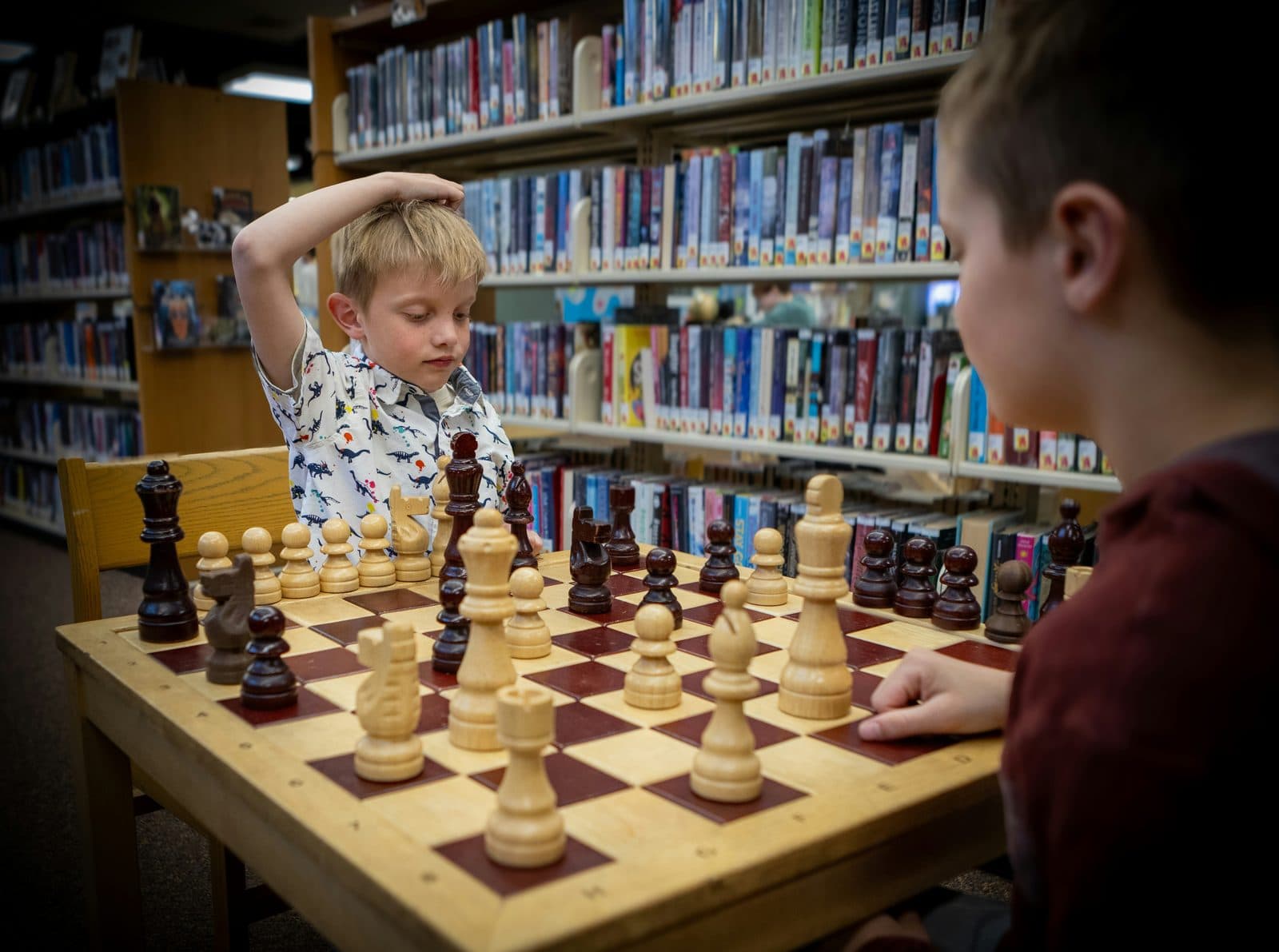 Two children playing chess in a library